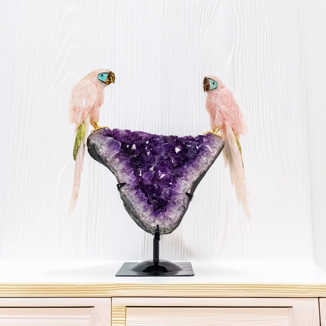 Escultura "Guacamayo Sagrado" en Cuarzo Rosa con Detalles en Serpentinita, Amazonita y Ojo de Tigre sobre Drusa de Amatista – 8,7kg